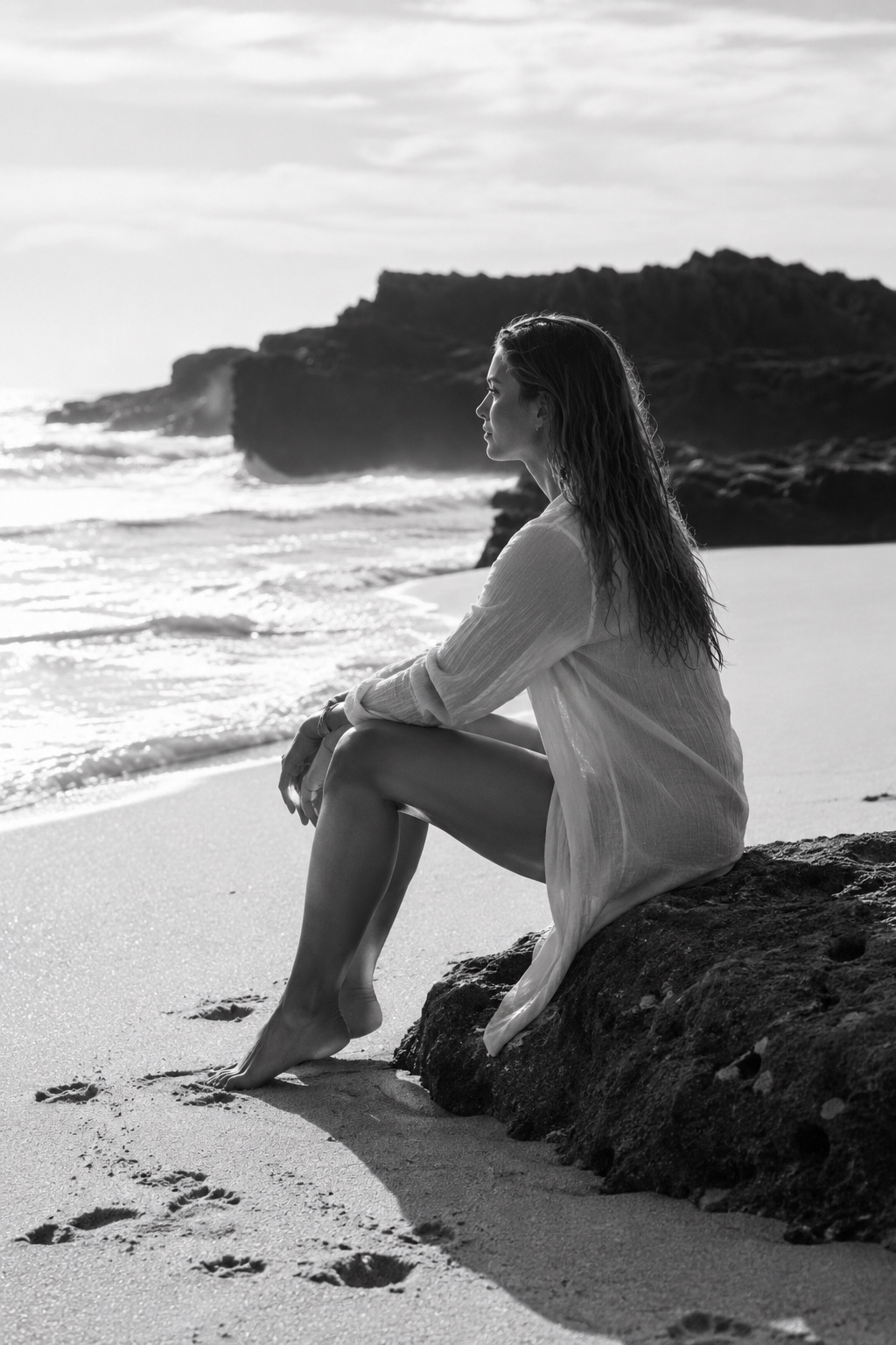 Mila sitzt am Strand auf einem Felsen